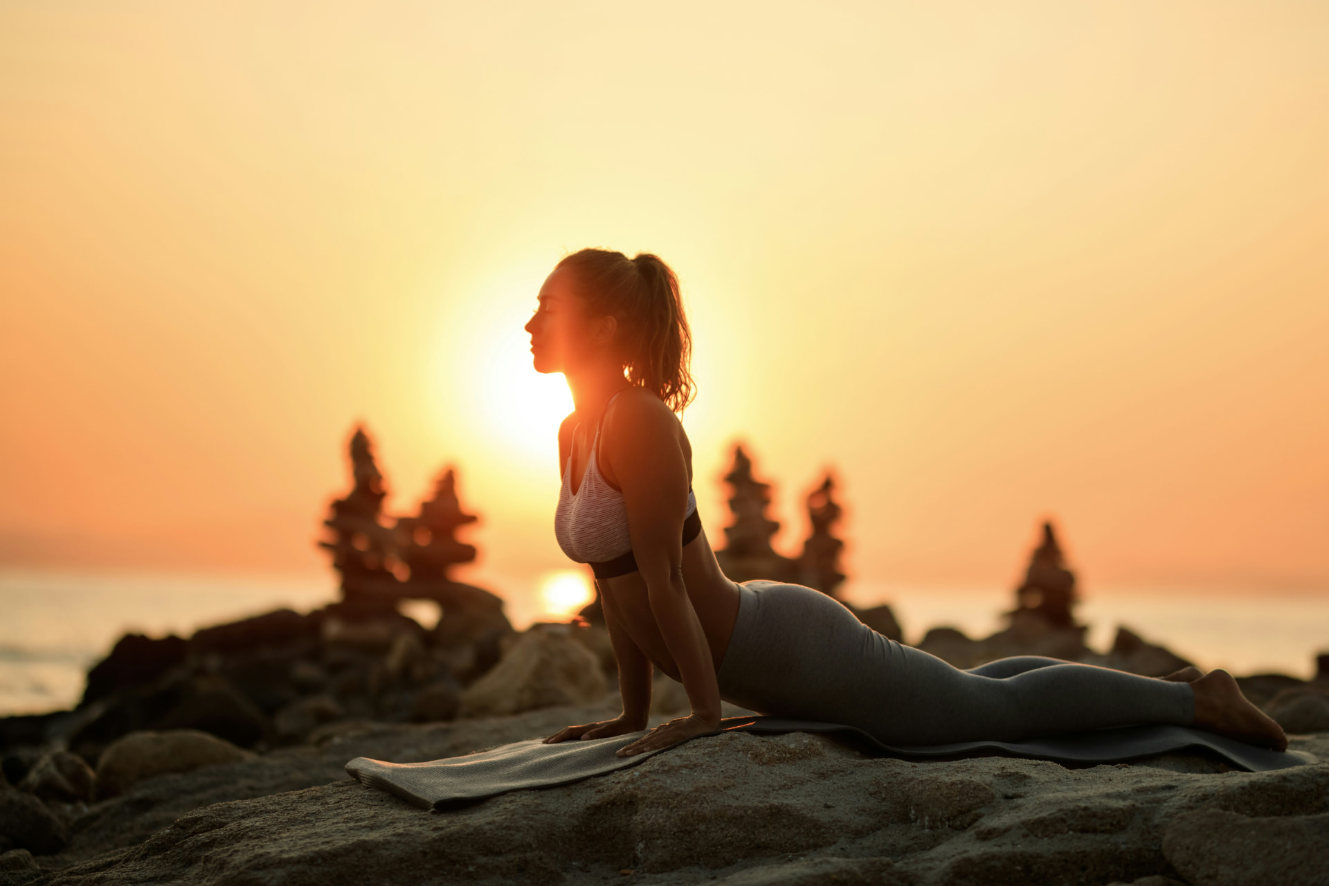 Person practising yoga at sunrise by the sea